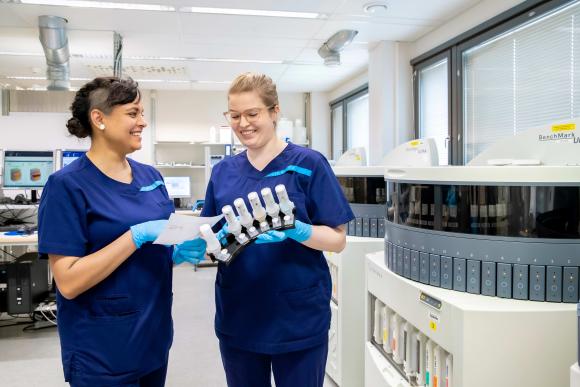 Två bioanalytiker tittar på forskningsresultat i laboratoriets lokaler.