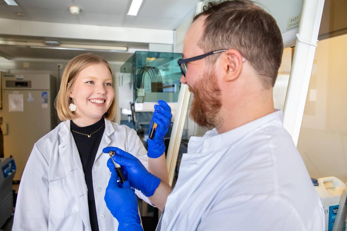 Two researchers in a laboratory holding sample tubes in their hands.